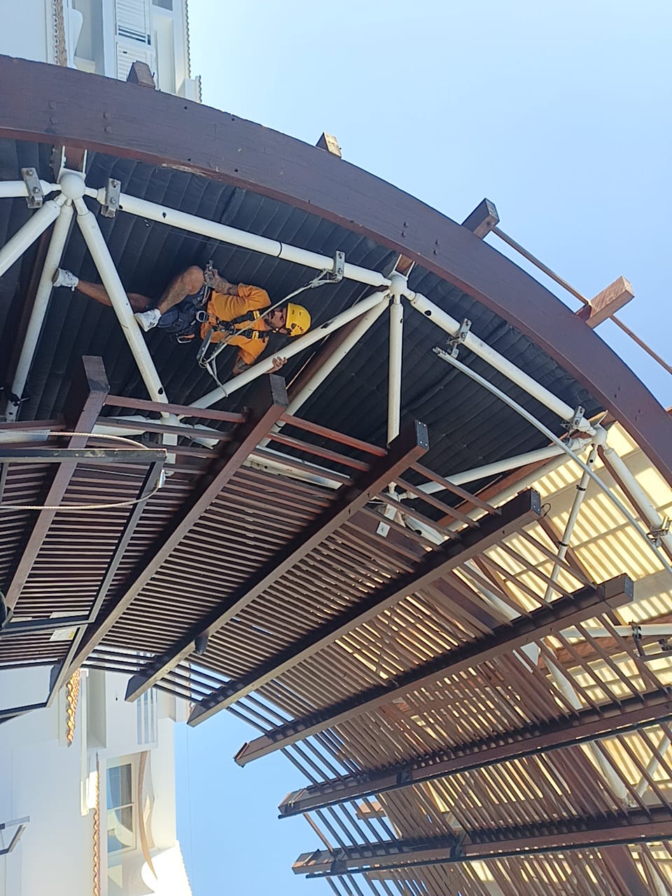 Técnico con arnés y casco accediendo a una estructura