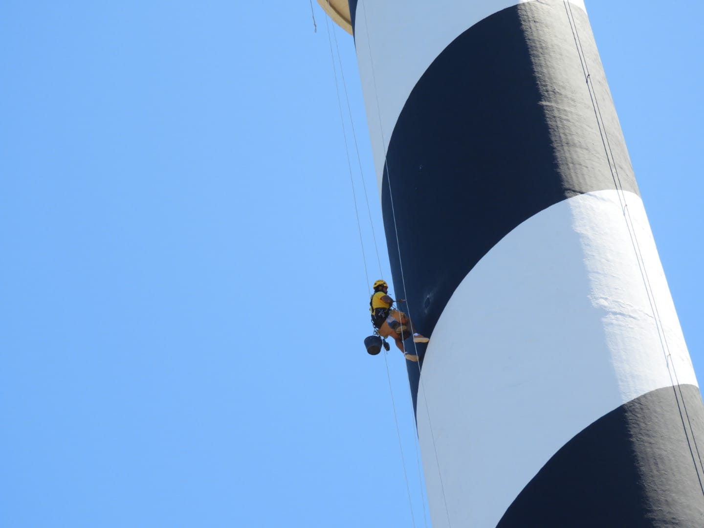 Técnico suspendido mediante cuerdas trabajando en un faro